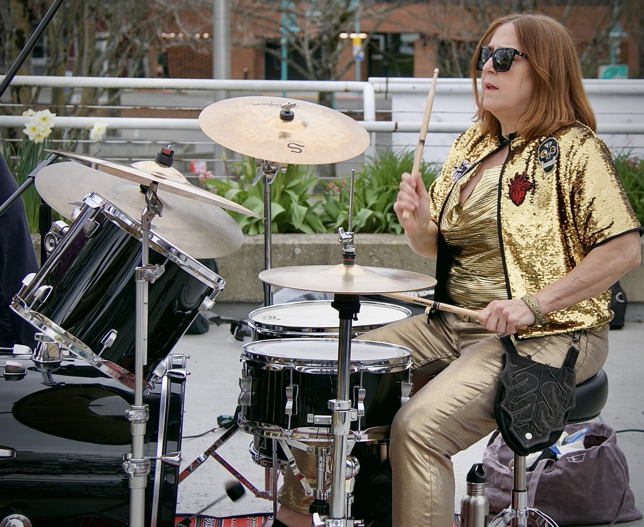 Person wearing metallic gold clothes playing a drum kit.